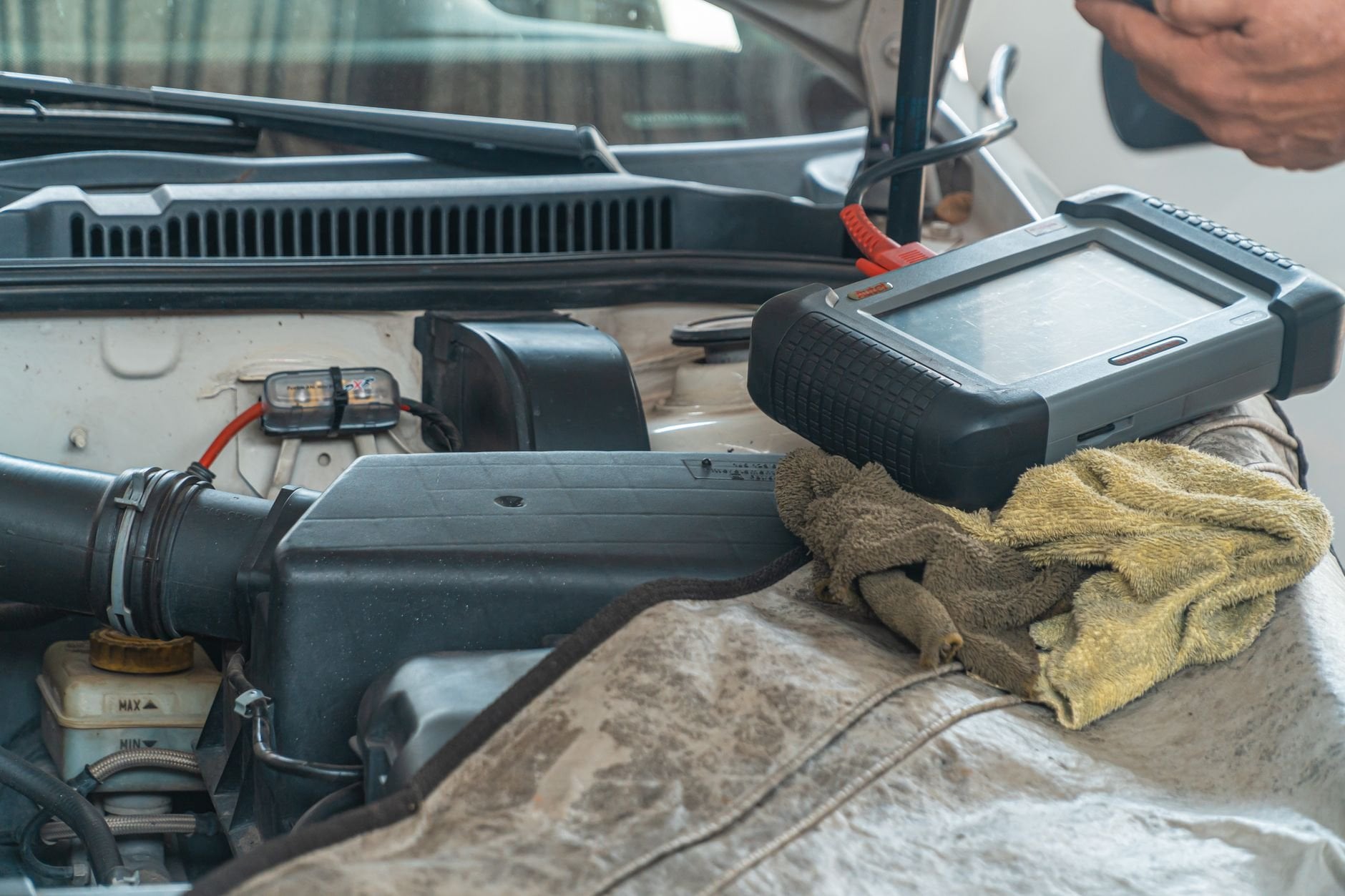 Mechanic using diagnostic scanner on car engine bay